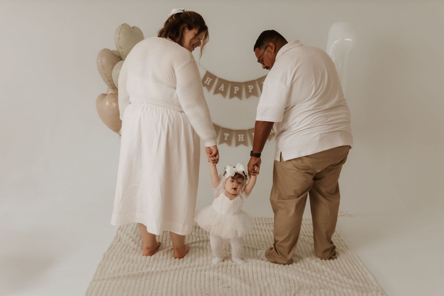 Family gathering under rustic birthday decorations in neutral toned room.