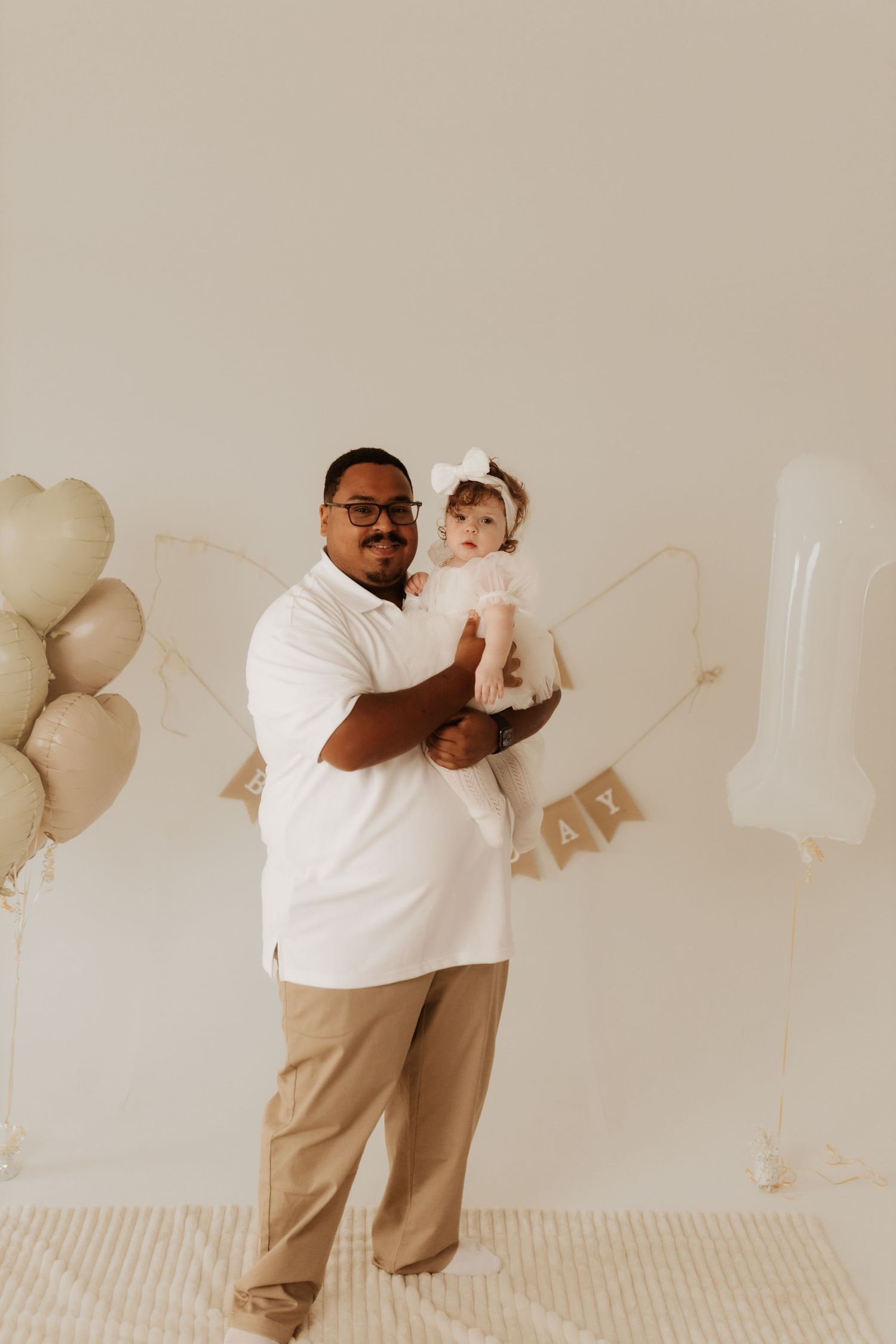 Family photoshoot series with coordinated neutral outfits and decorative balloons in the background.