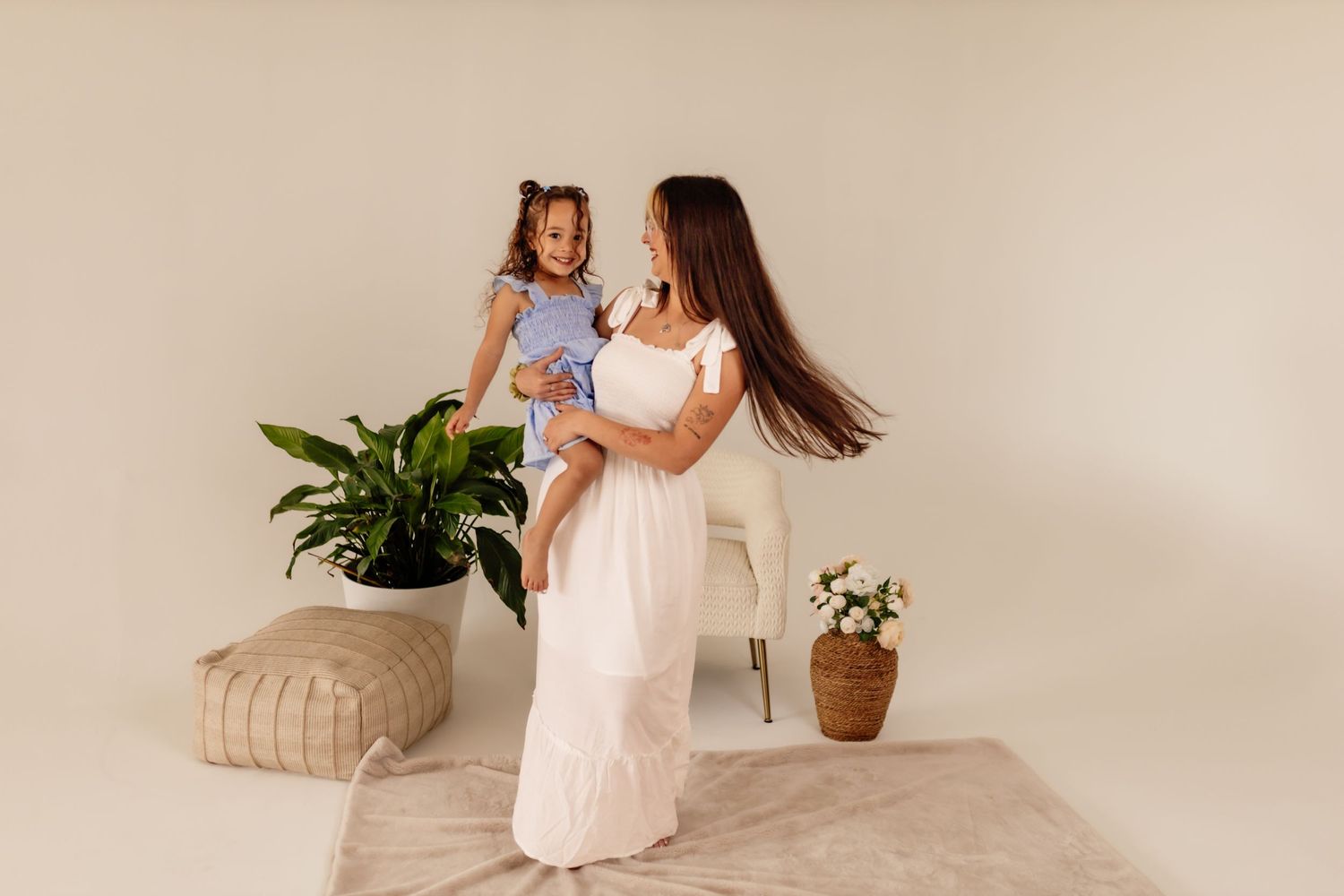 Lifestyle family photography with white dress and decorative plants in minimalist setting.