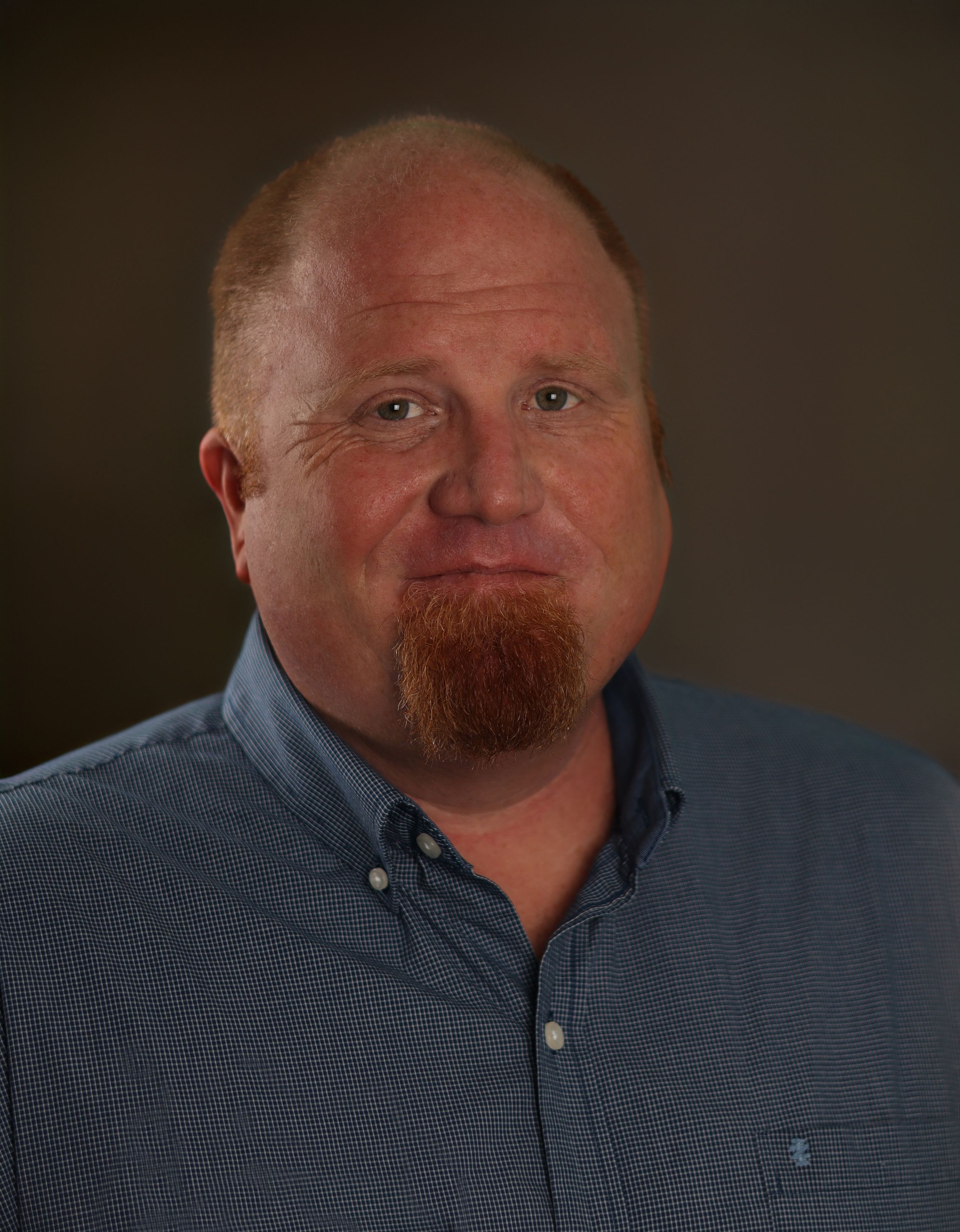 Male headshot photograph on a tan background.