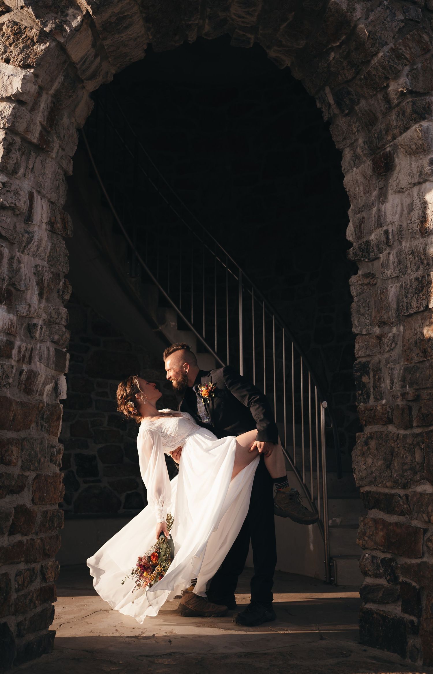 A couple dances in a golden field at sunset with a flowing white dress creating movement.
