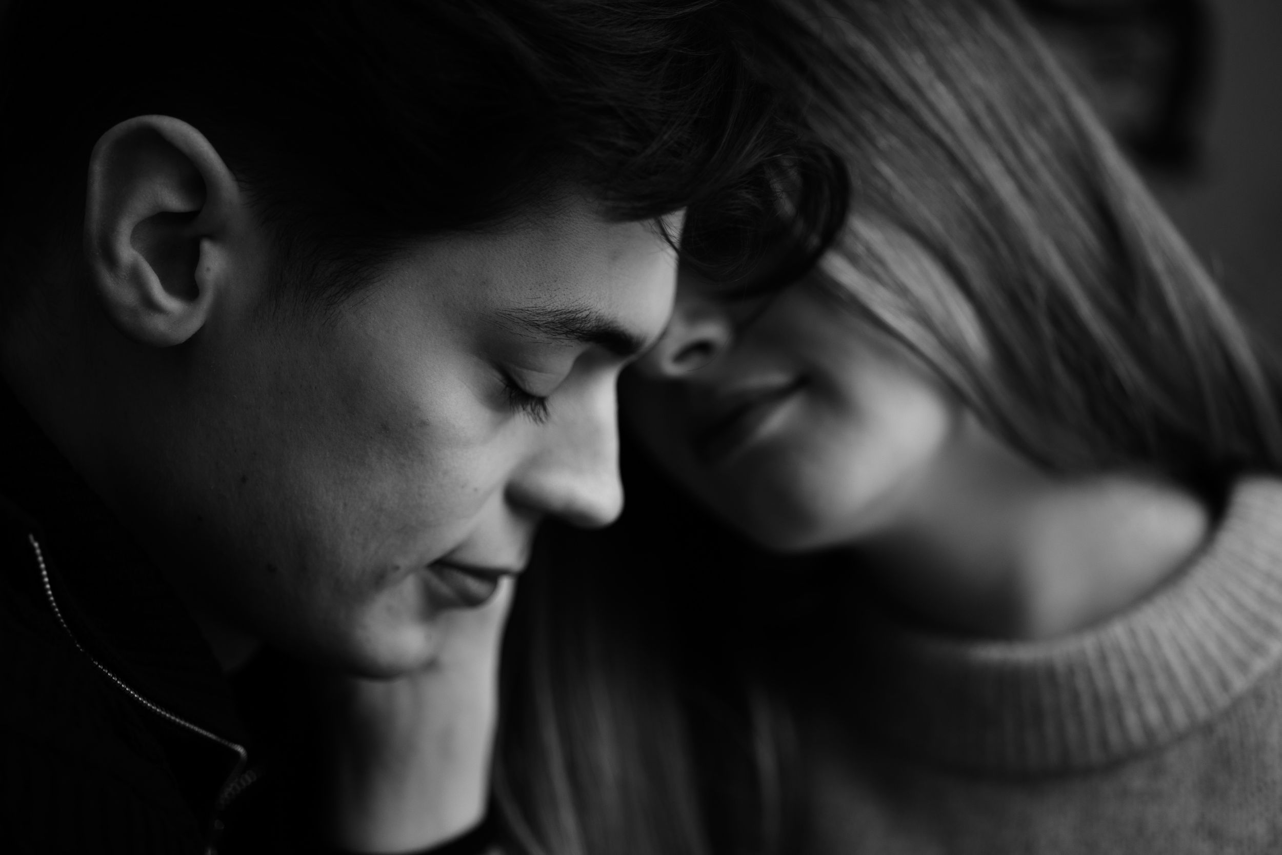A black and white portrait capturing an intimate moment between two people in profile.