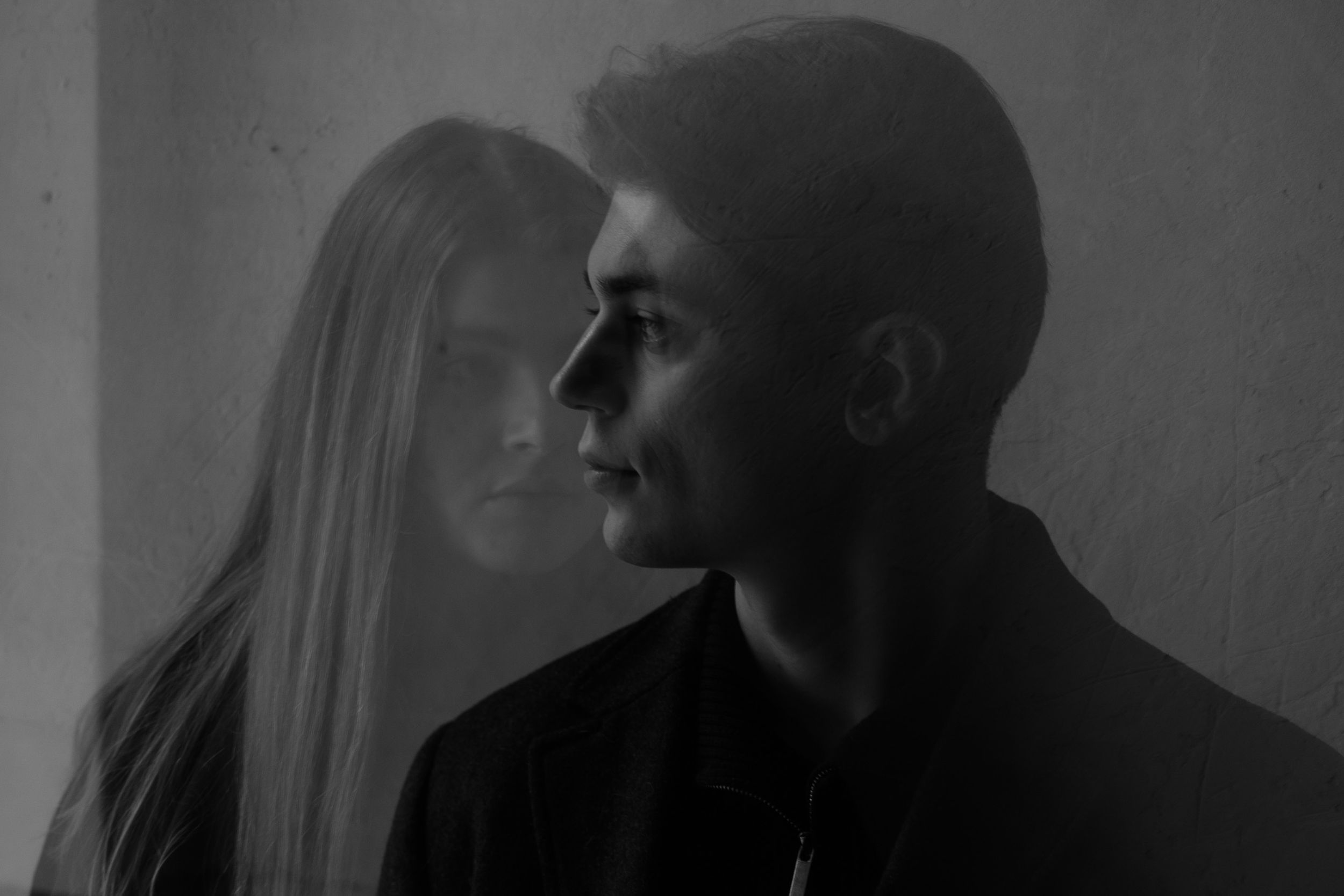 A black and white artistic profile portrait of two people in silhouette against a light background.