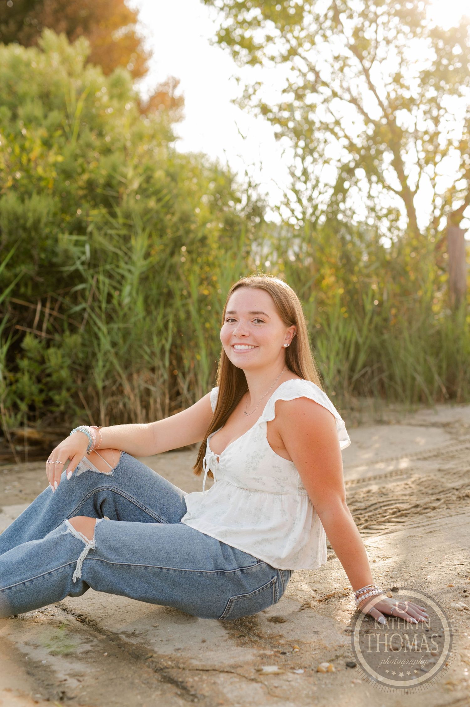 A relaxed outdoor portrait near tall grass and trees during golden hour.