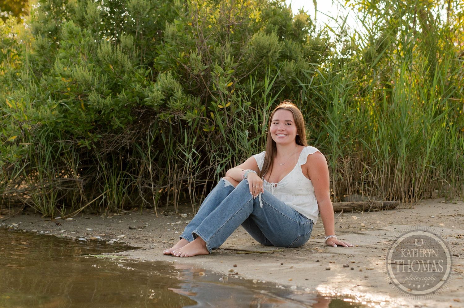A relaxed outdoor portrait by the water's edge during sunset.