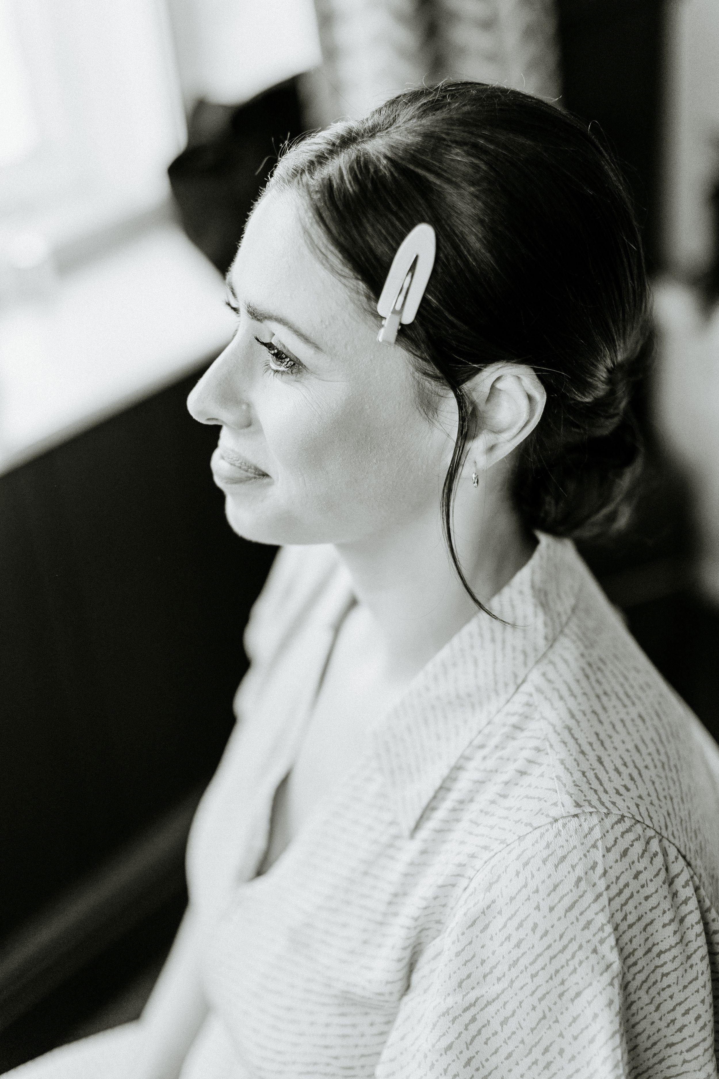 Black and white profile portrait showing hair with a decorative clip while wearing a textured sweater.