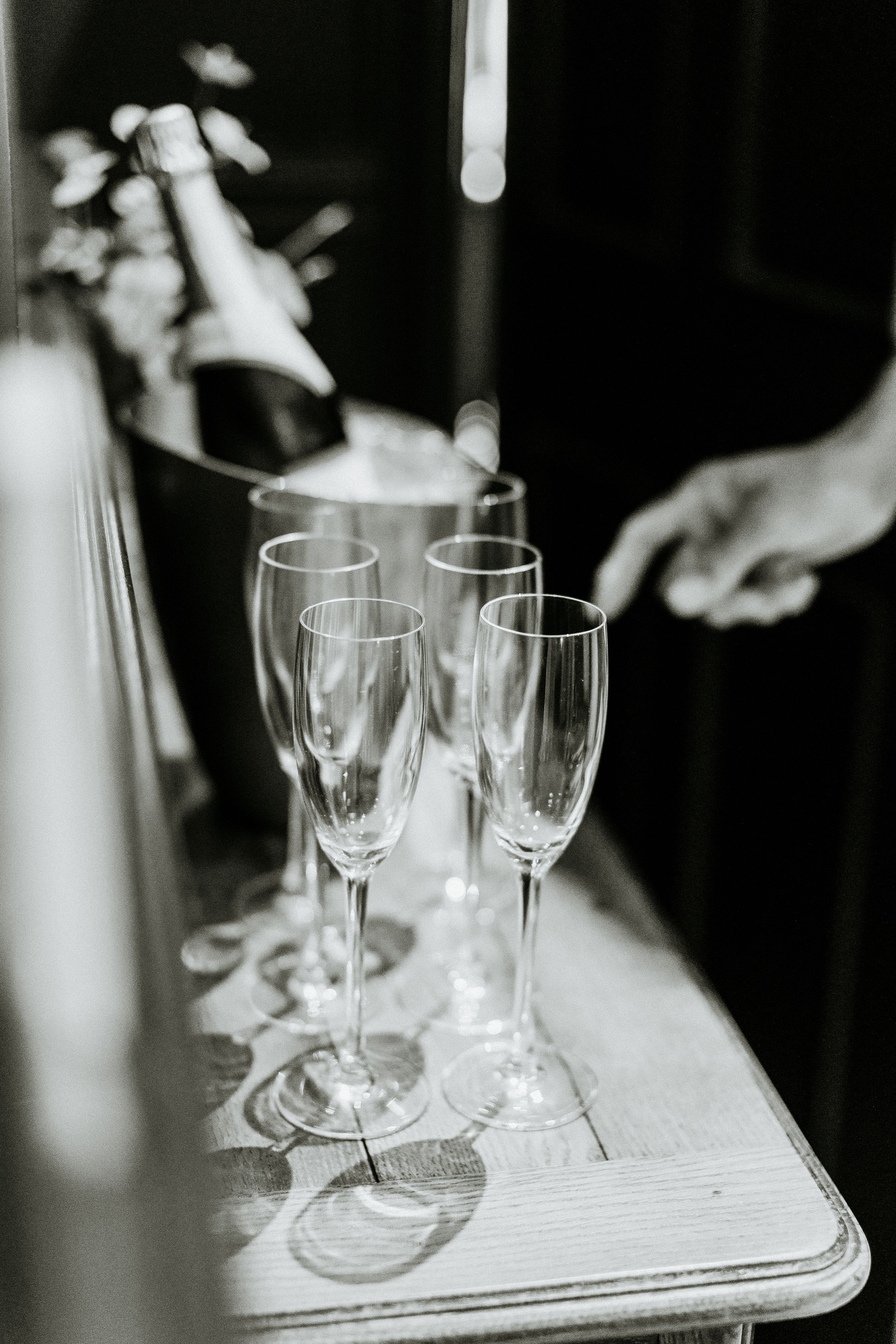 Black and white photo of empty champagne flutes on a table during an elegant event preparation.