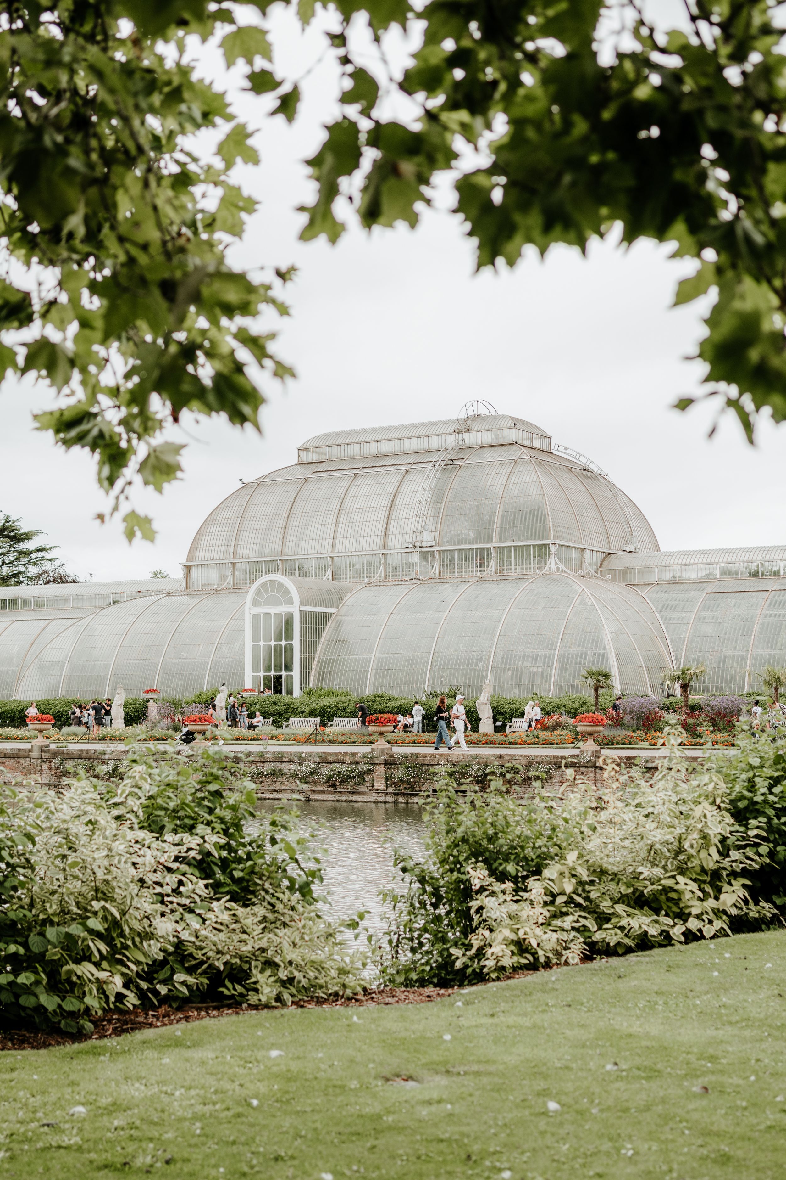 A grand greenhouse conservatory with a glass dome exterior surrounded by manicured gardens.