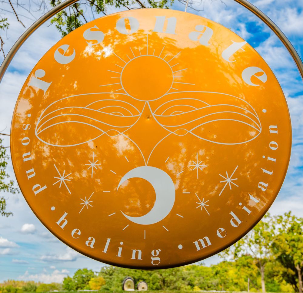 A circular orange meditation disk with celestial designs featuring a sun, moon, and stars pattern against a blue sky background.