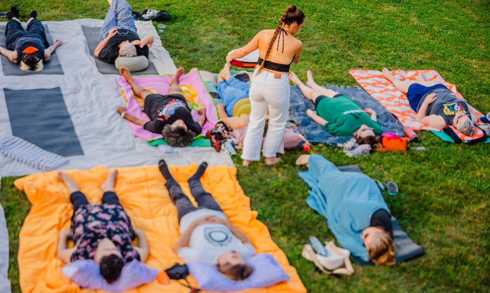 People relaxing on colorful blankets during an outdoor sound therapy session.