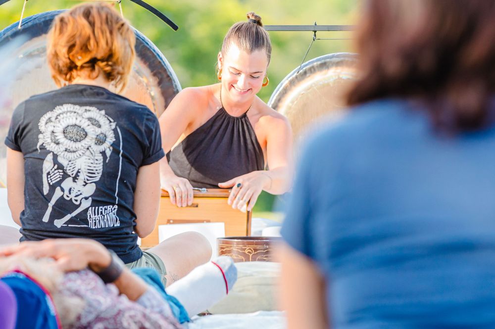 Sound healing demonstration with singing bowls and gongs in an outdoor setting.
