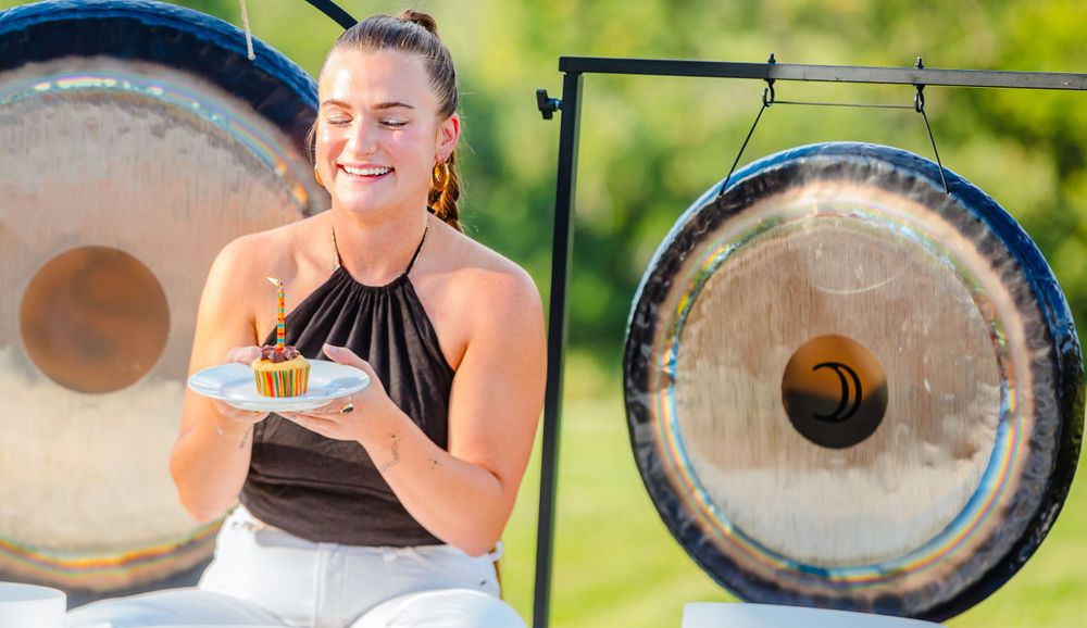 Sound healer with meditation bowls and gongs performs during an outdoor wellness session.