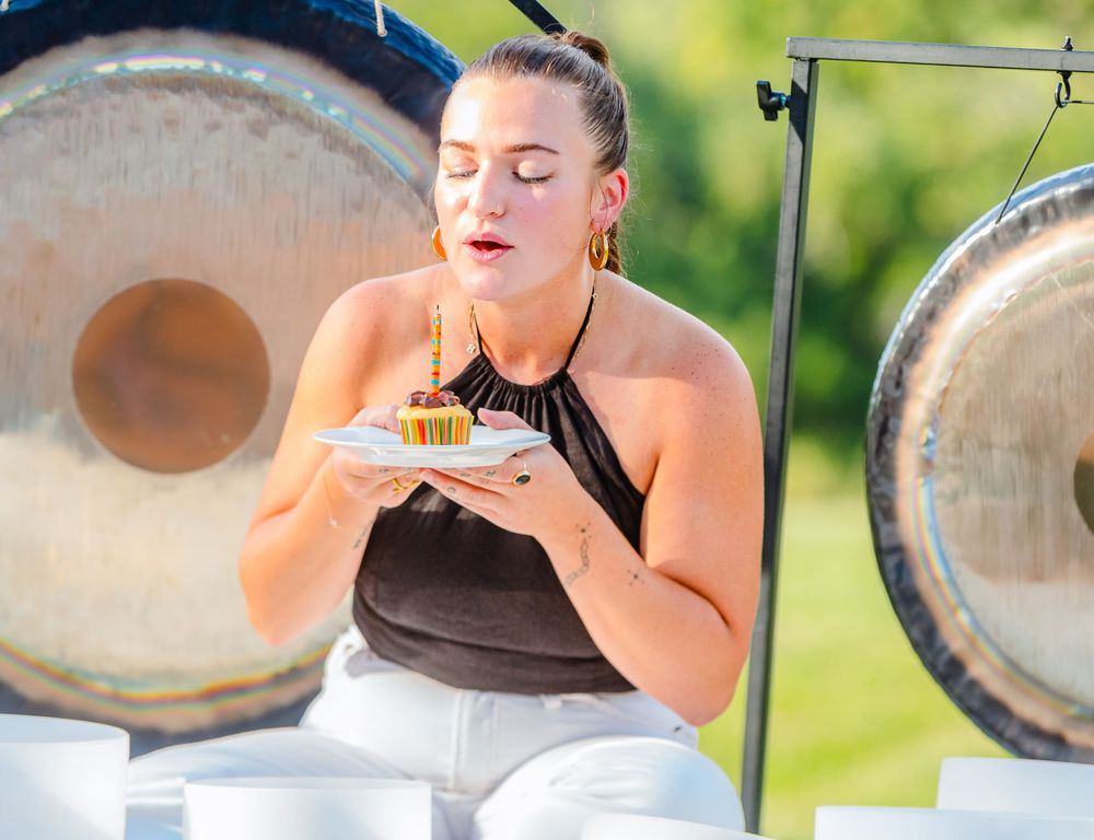 Someone enjoying a snack while sitting near large gongs during an outdoor meditation session.