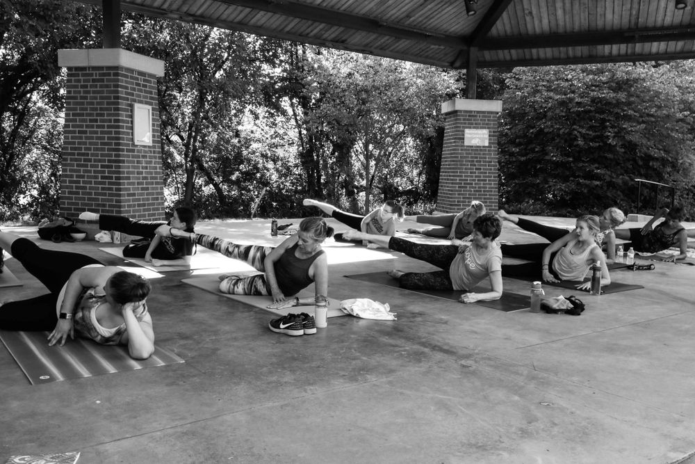 People doing exercises outdoors under a covered area in a vintage black and white photograph.