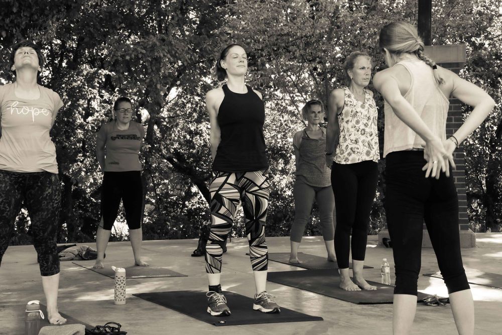 A group of people exercising together outdoors in workout attire during a fitness class.