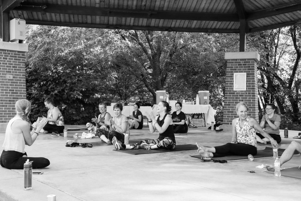 A group of people gathered under a covered outdoor area with musical instruments in a black and white photograph.