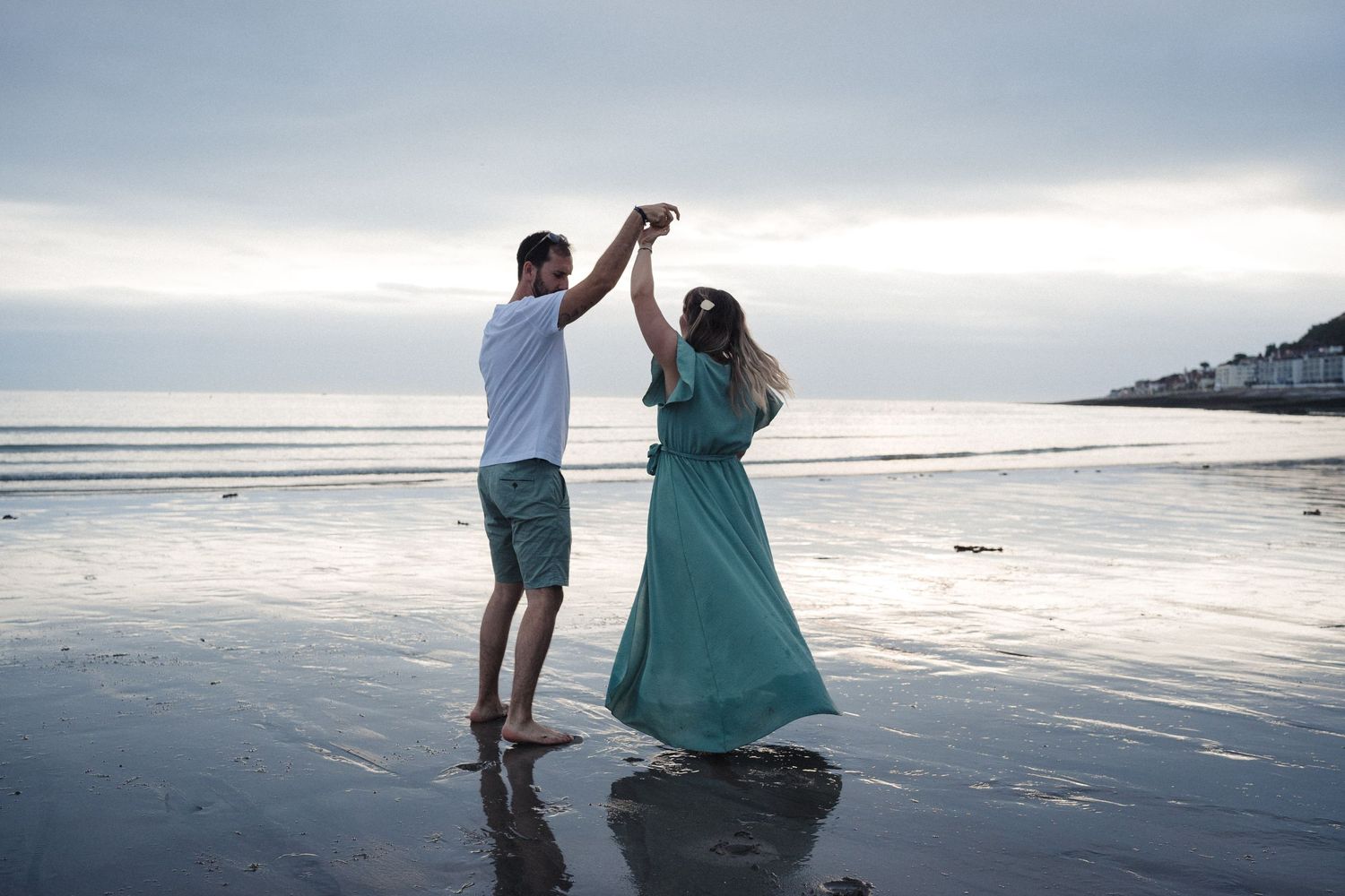 Couple dancing together on a misty beach at sunset in romantic pose.