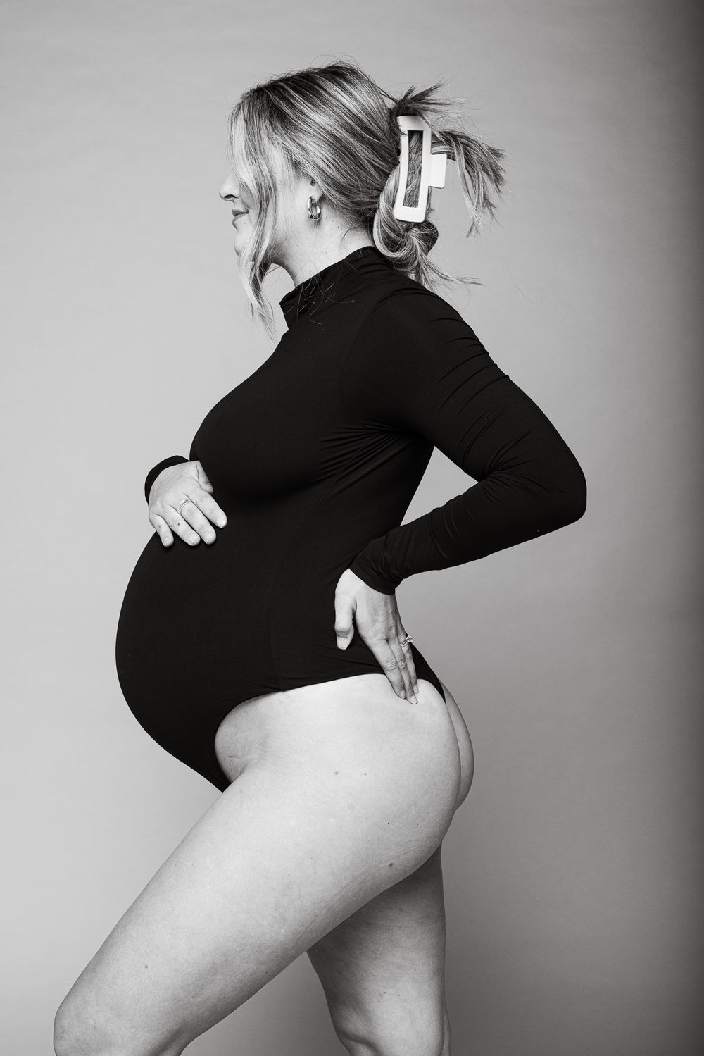 A side-profile maternity photo shows a pregnant figure in black turtleneck against gray background.