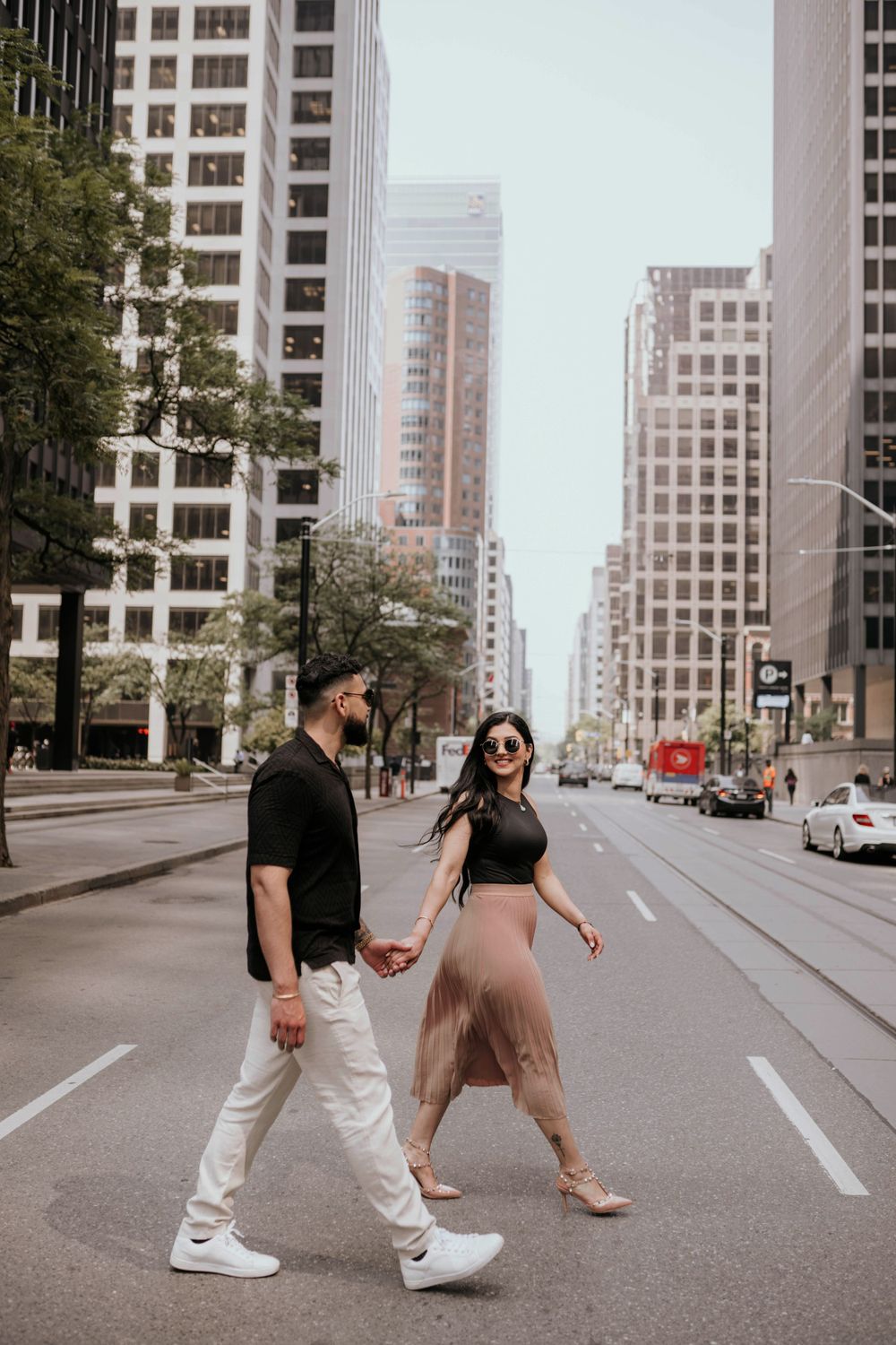 A couple walks hand in hand down an urban street lined with tall buildings in downtown Chicago.