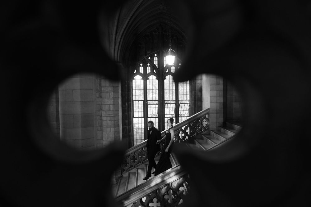A dramatic black and white view through a circular window showing gothic church architecture with stained glass windows.