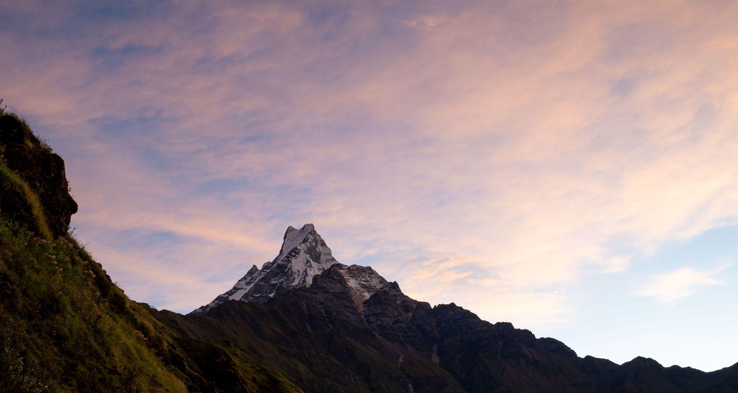 Dramatic sunset sky over snow-capped mountain peaks in a panoramic landscape view.