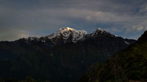 Majestic snow-covered mountain peaks under dramatic cloudy sky.