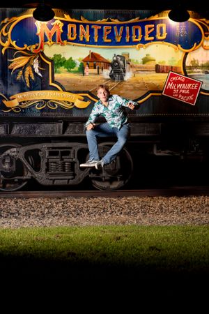 Person sits on a train car beneath illuminated vintage Montevideo sign with western-themed artwork.
