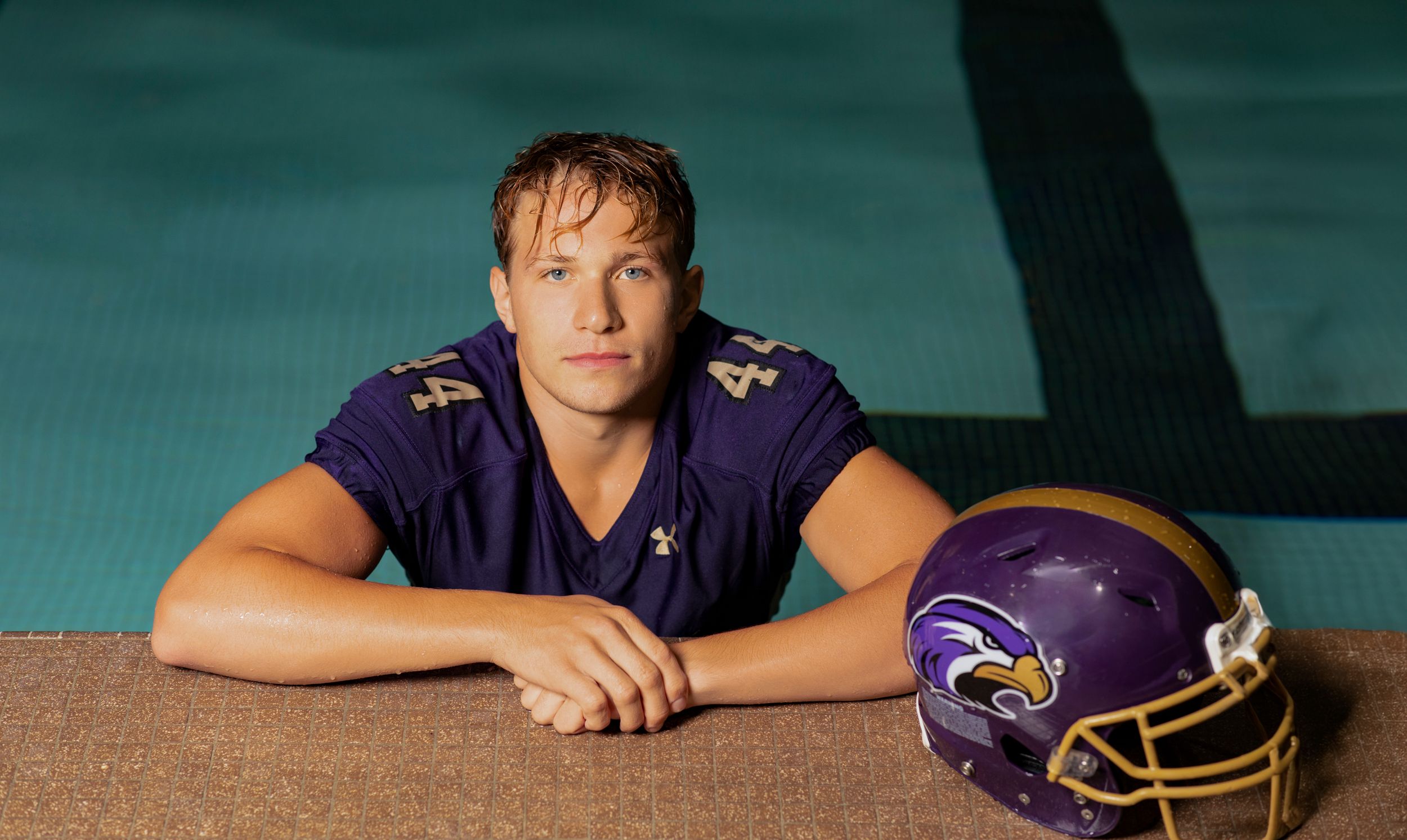Minnesota Vikings football player poses with purple team helmet against dramatic turquoise backdrop.