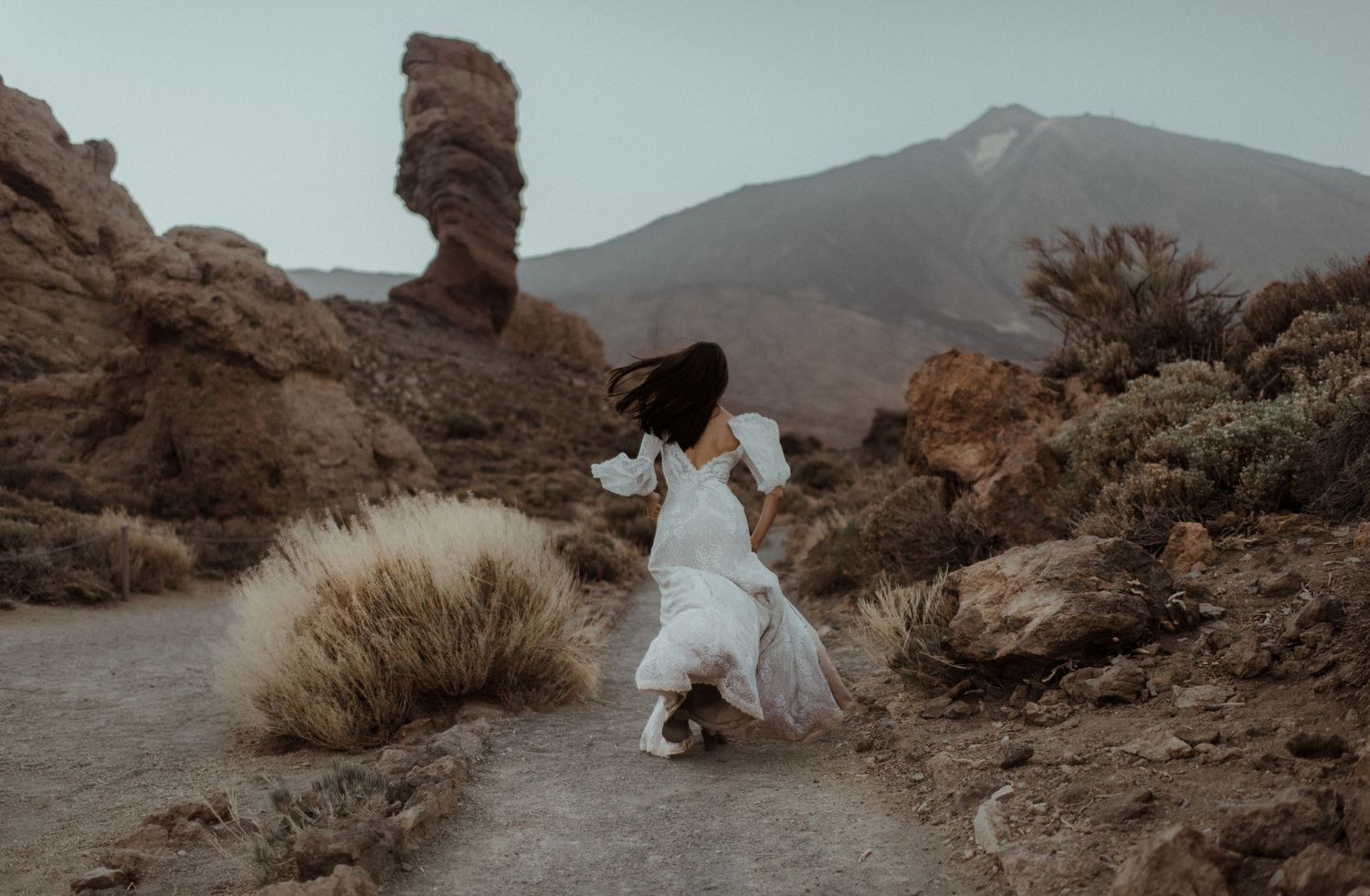 A whimsical desert scene with a white dress contrasting against rocky terrain and mountains.