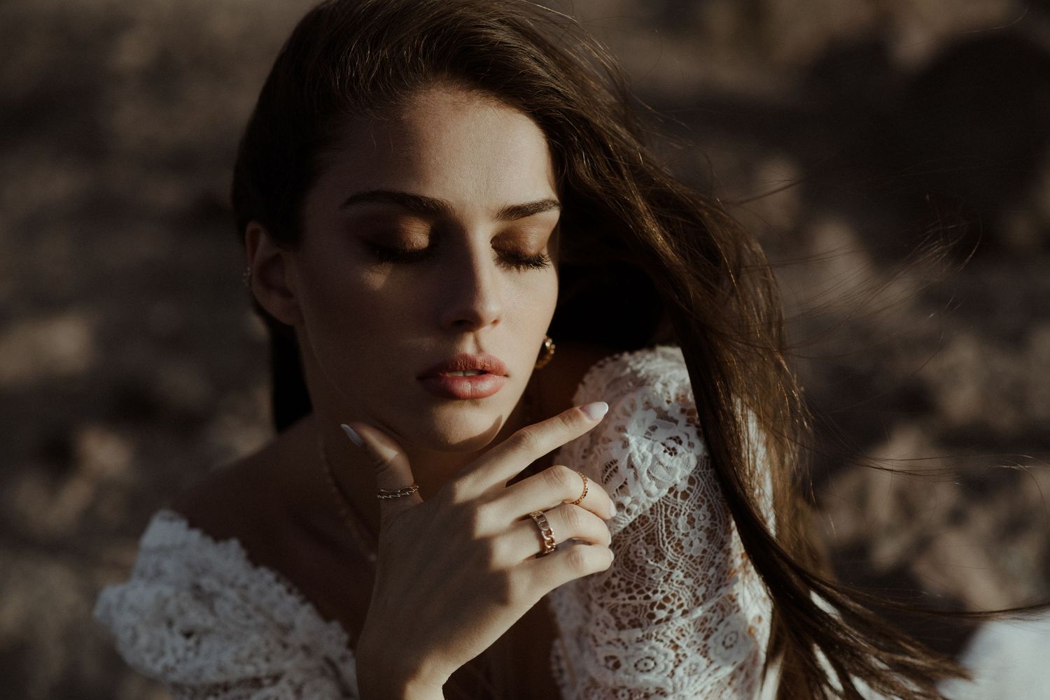 Close up of intricate lace wedding dress details against desert rocks.