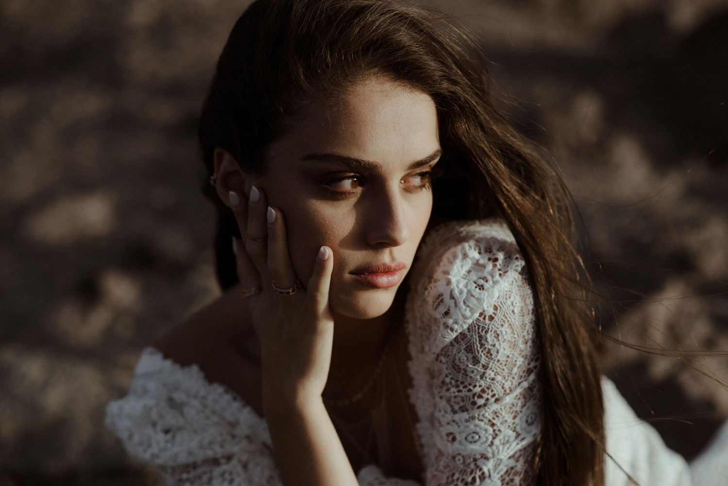 A moody portrait in a lace dress with dramatic lighting against a dark background.