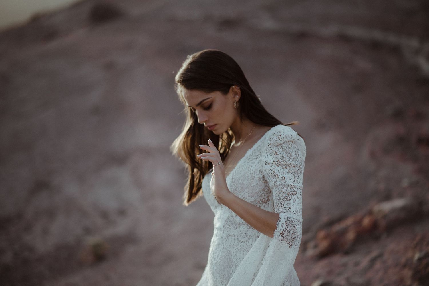 Atmospheric portrait in delicate white lace against desert rocks.