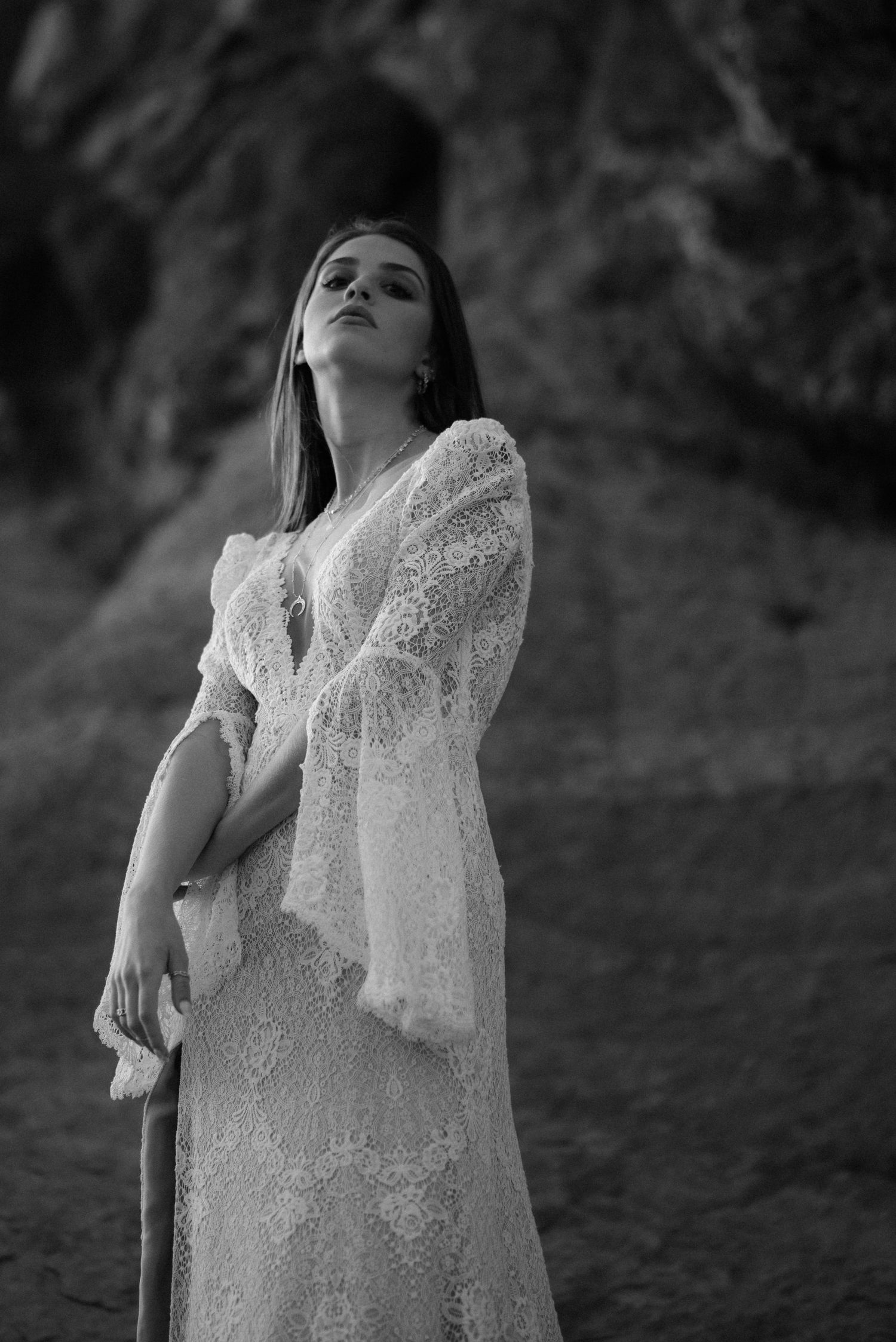 Dramatic black and white portrait in vintage lace against textured rock wall.