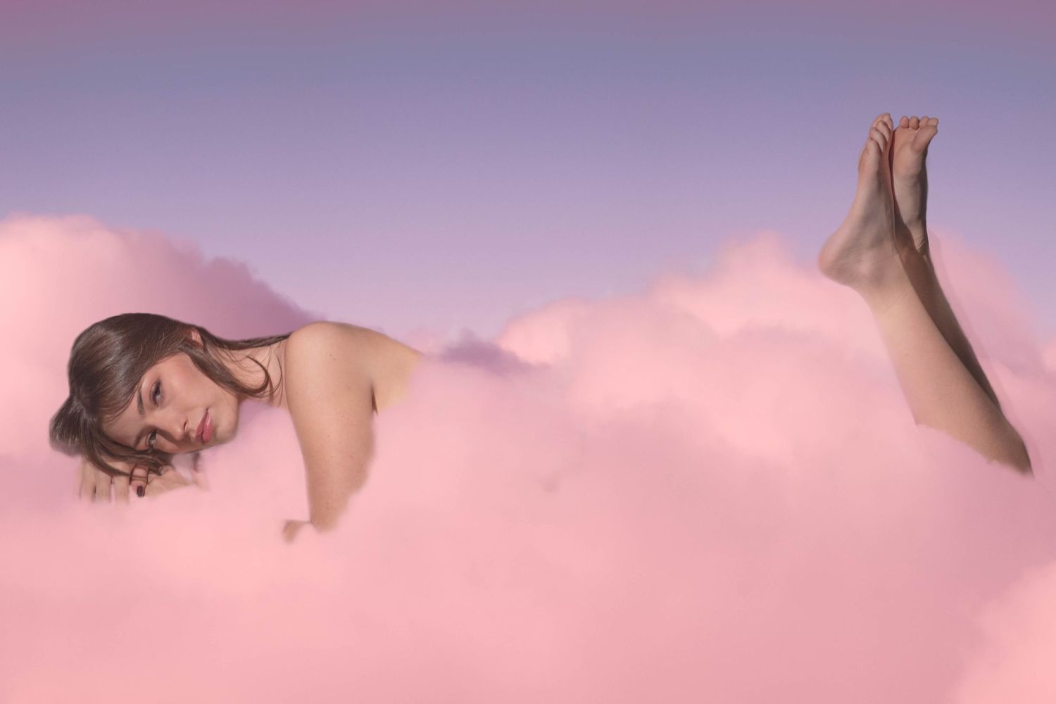 Young woman lying serenely among fluffy pink clouds against a soft purple gradient sky.