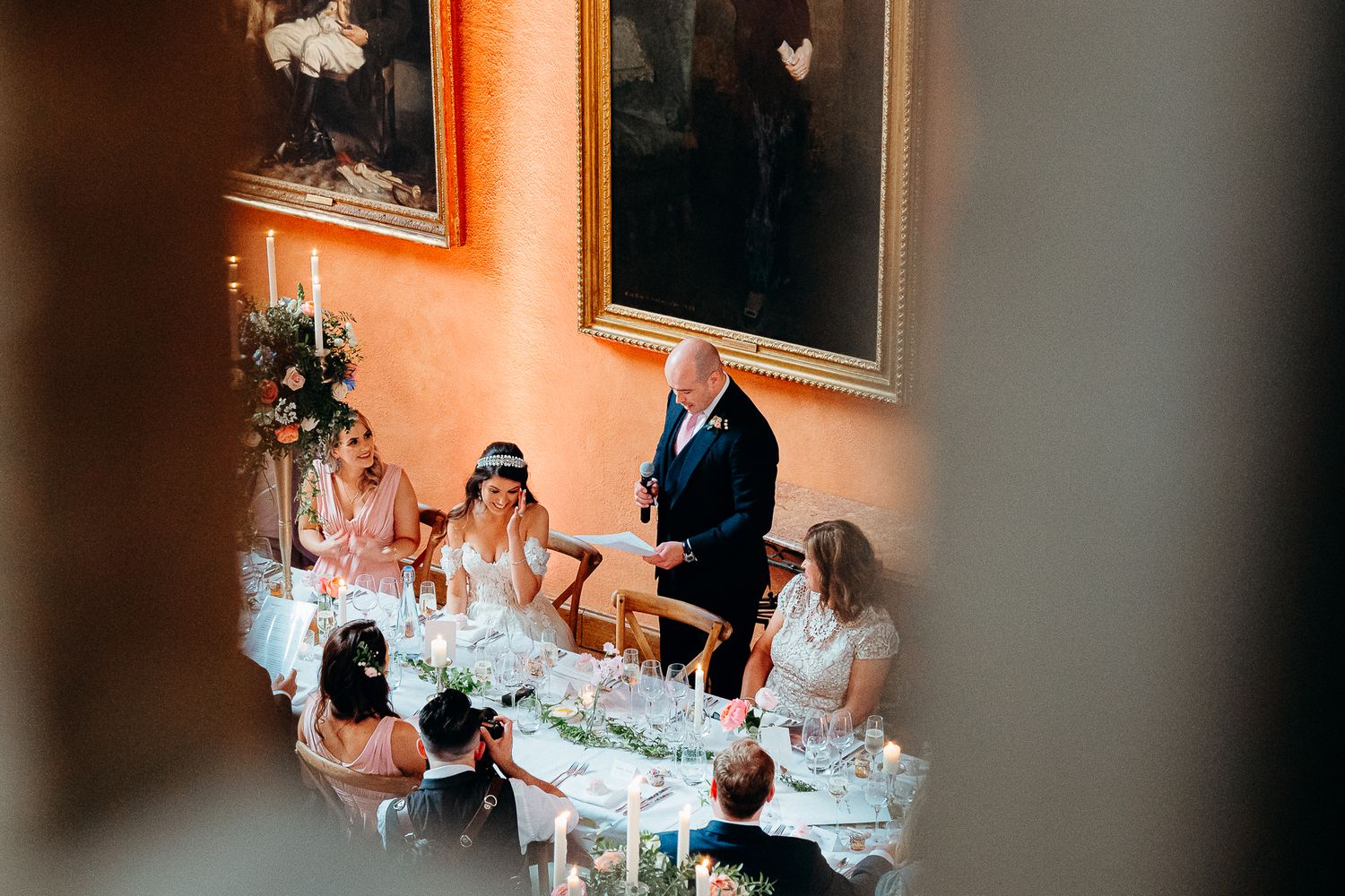 Overhead view of an elegant wedding reception dinner table with guests seated in formal attire.