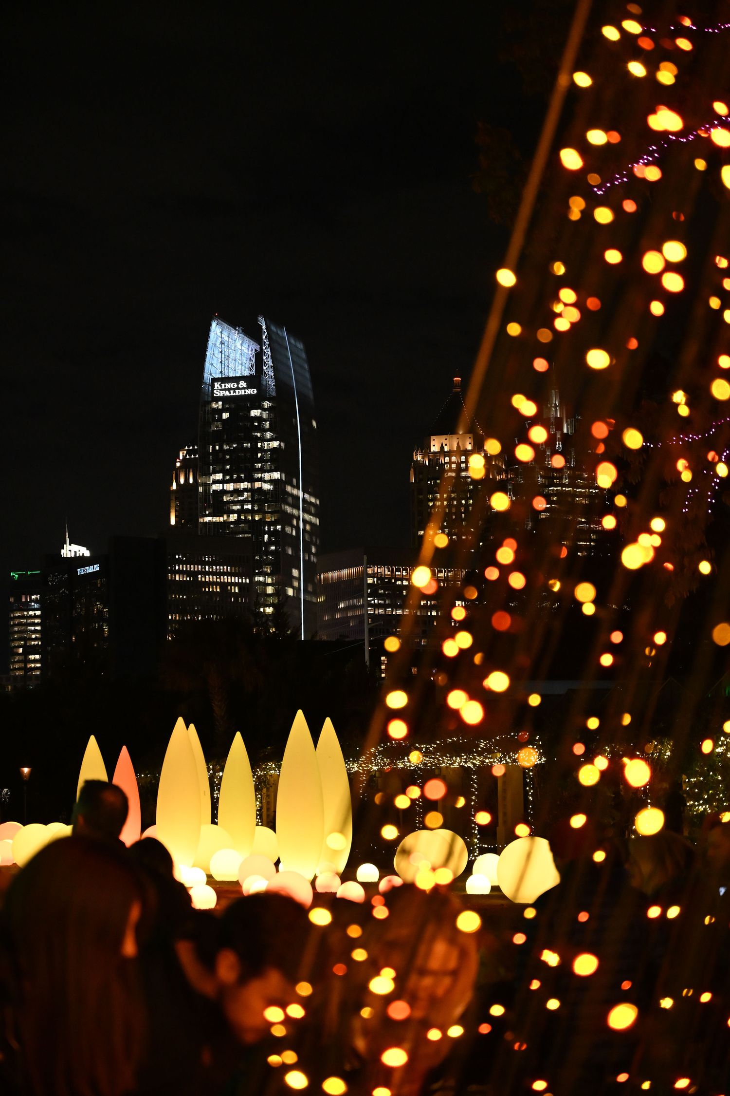 City skyline at night with illuminated buildings and glowing decorative lights creating a magical urban atmosphere.