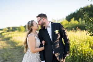 Joyful wedding couple sharing intimate moment in sunlit meadow.