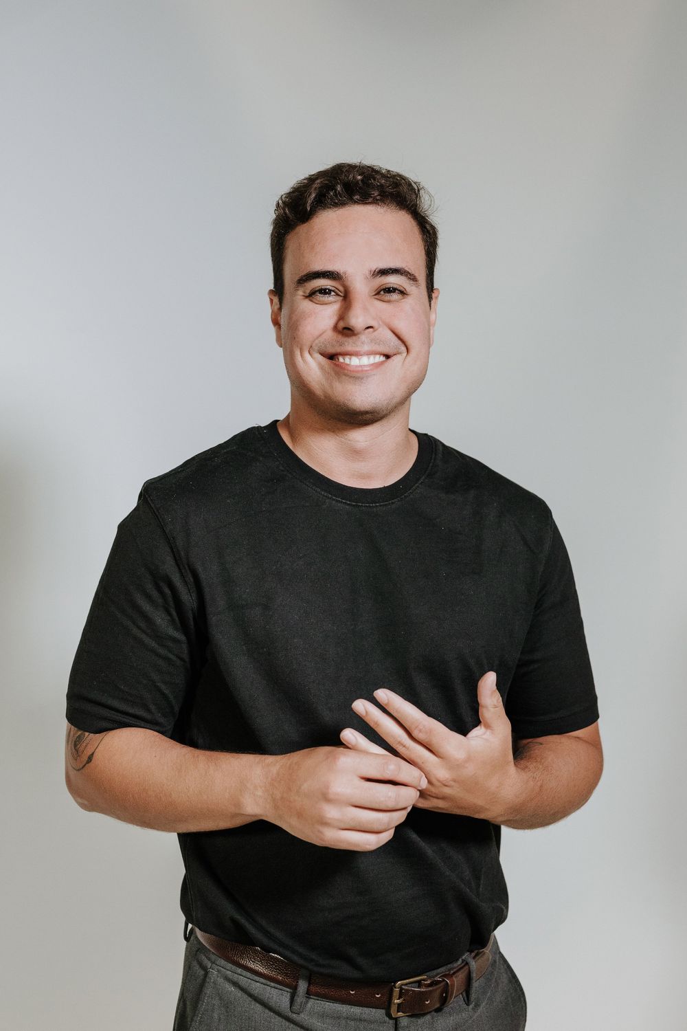 A person in a black t-shirt poses against a light gray background in a series of expressive portraits.