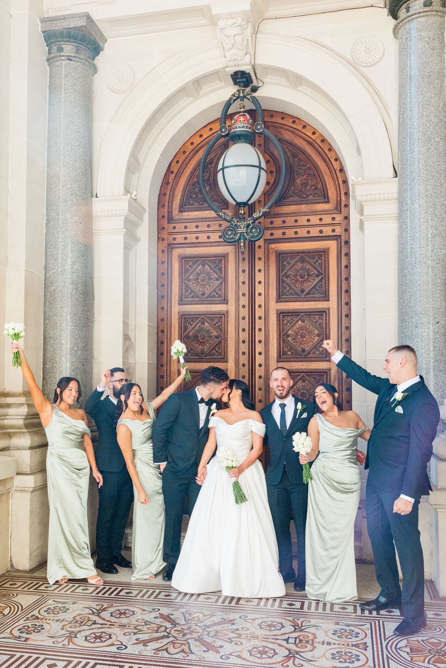 A happy couple shares joyful laughter during their outdoor wedding photo session surrounded by lush greenery.