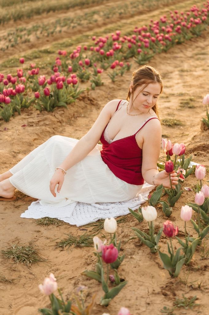 A dreamy photoshoot in a pink tulip field featuring burgundy and white spring dresses against a rustic backdrop.