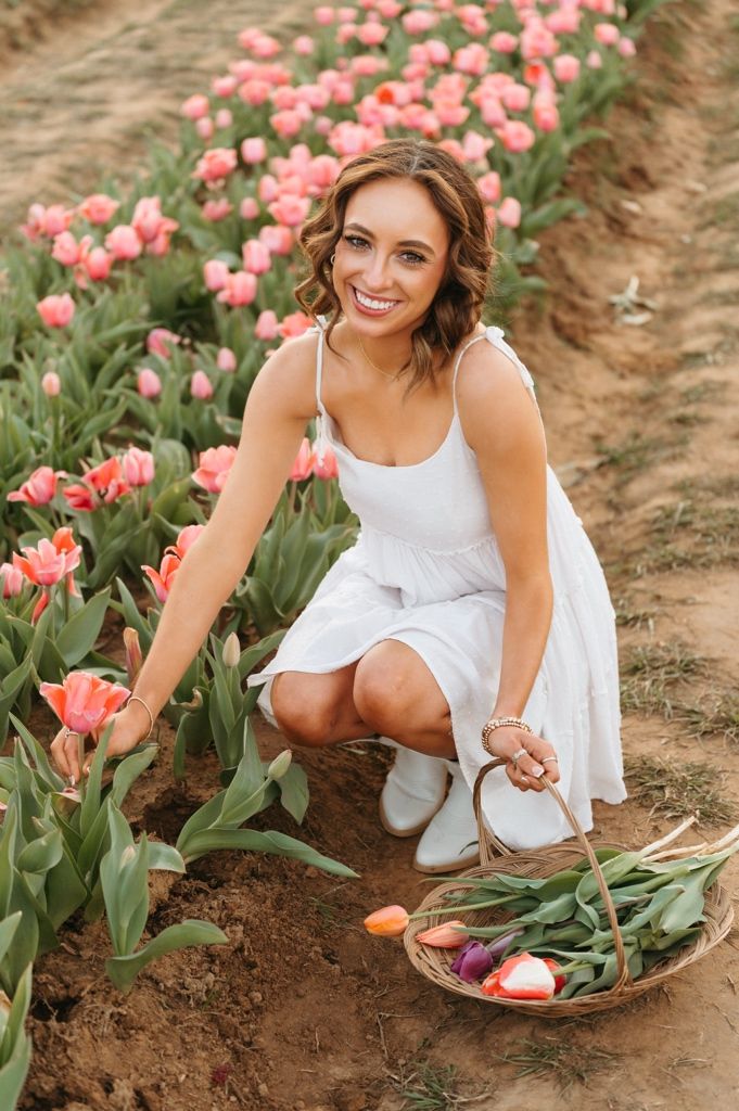White-dressed figure picking pink tulips in a garden field during a spring photoshoot.