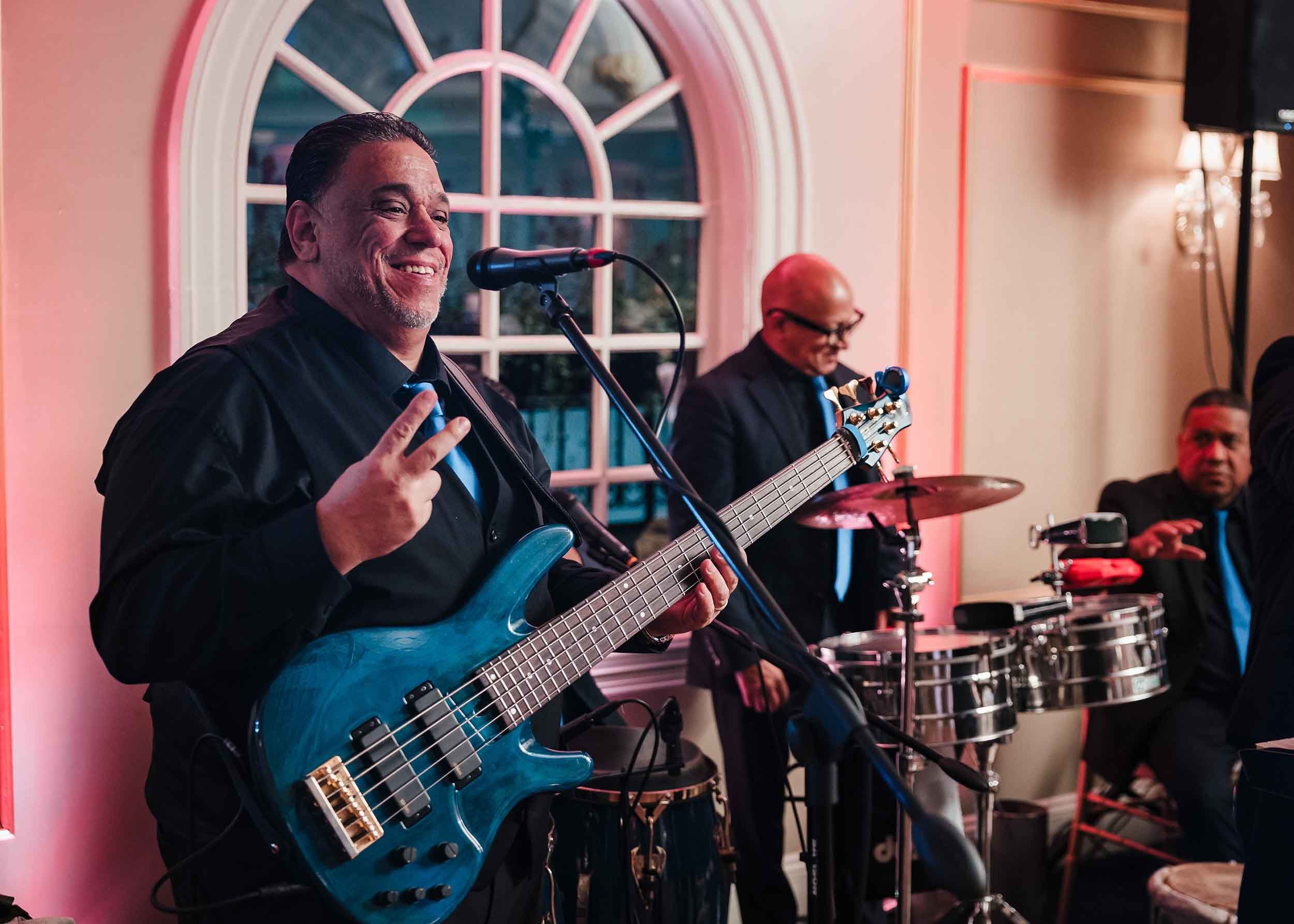 Bassist smiling and engaging with guests during a Grupo Chevere performance at a Lenox Hotel Boston wedding.