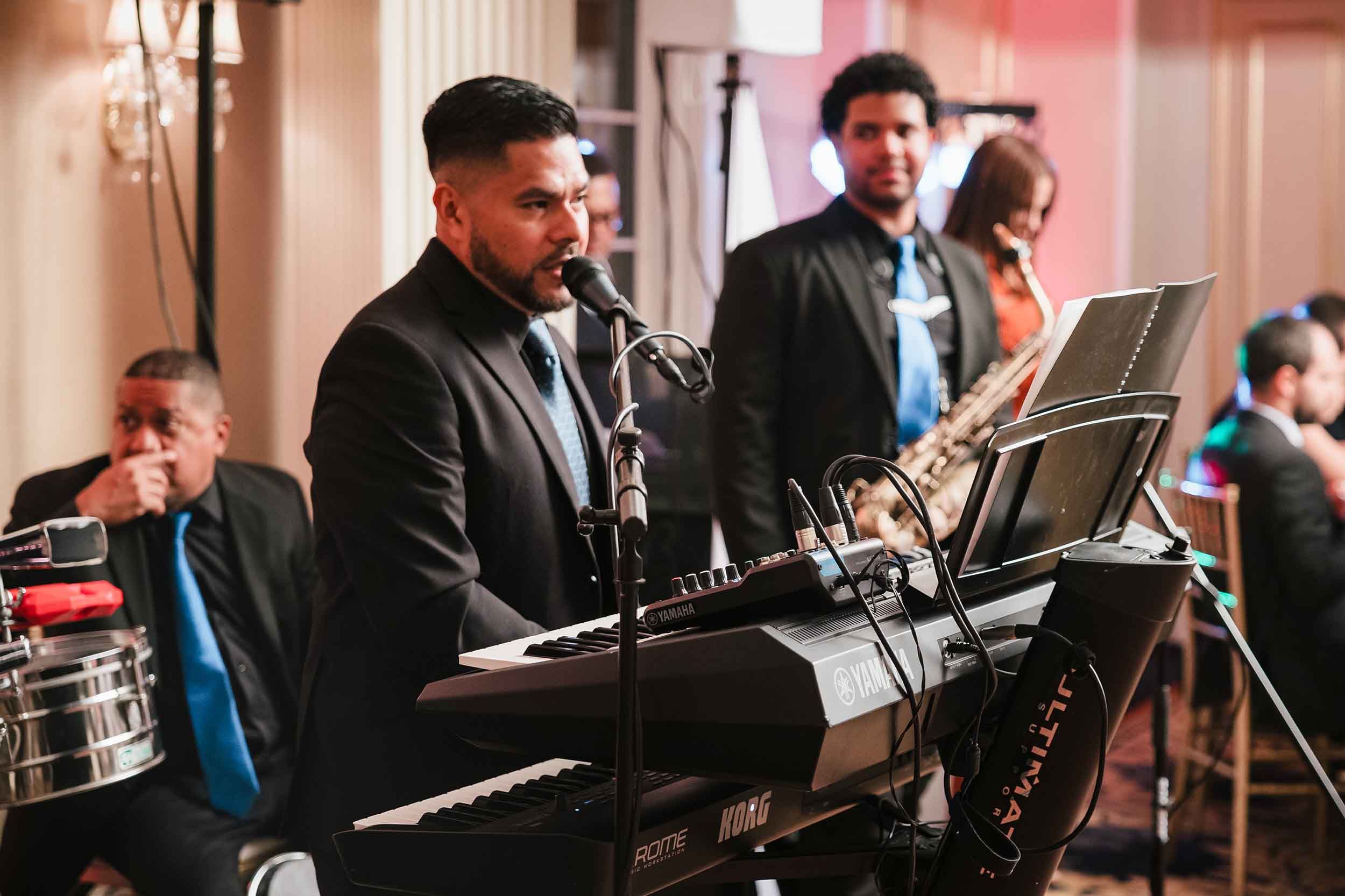 Lead singer performing at the keyboard with Grupo Chevere during a lively Boston wedding reception