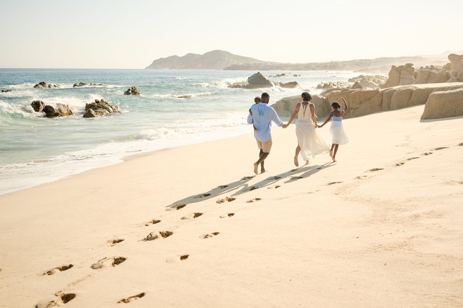 Puerto Vallarta family photography, family running on the beach with palm trees and bright blue tropical sky at sunset.