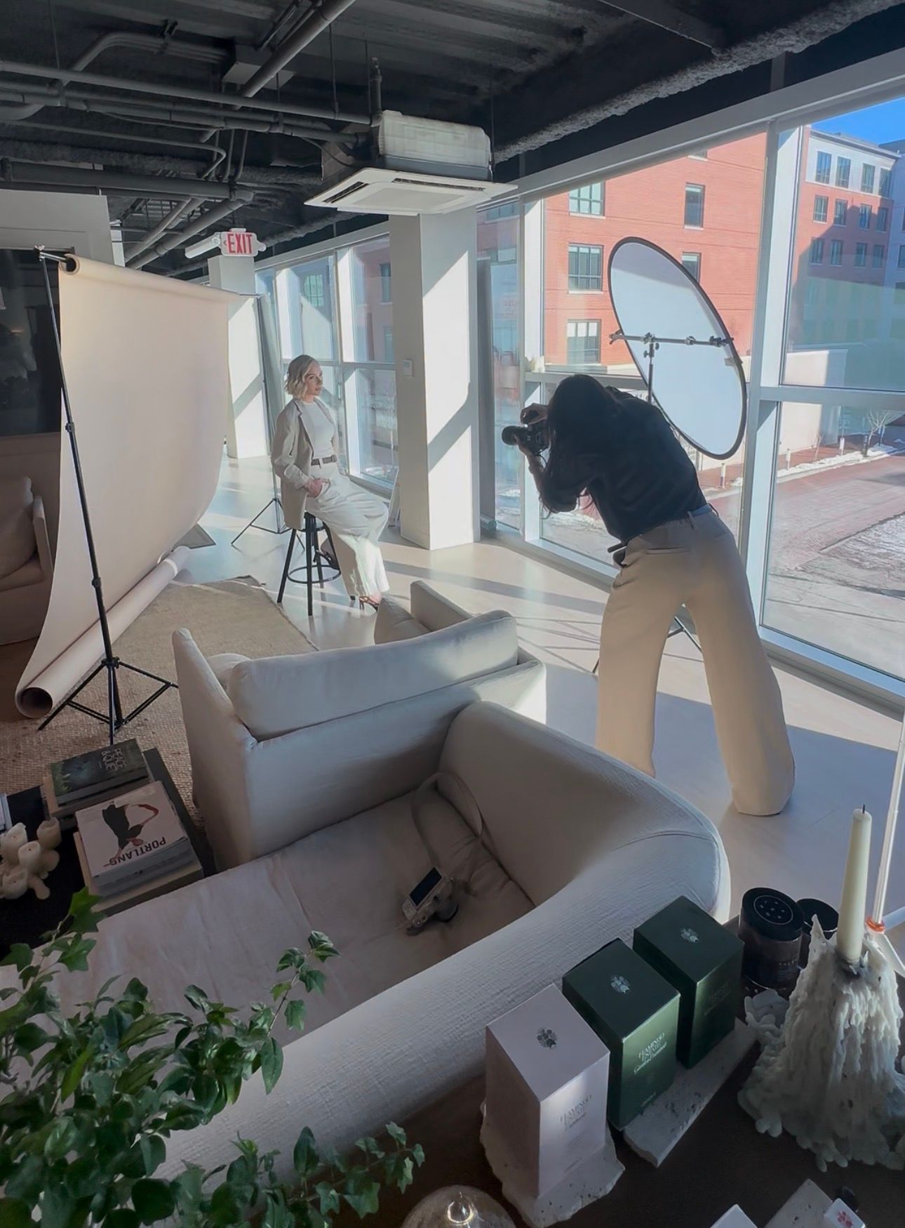 Person setting up photography equipment in a bright office space with windows and indoor plants.