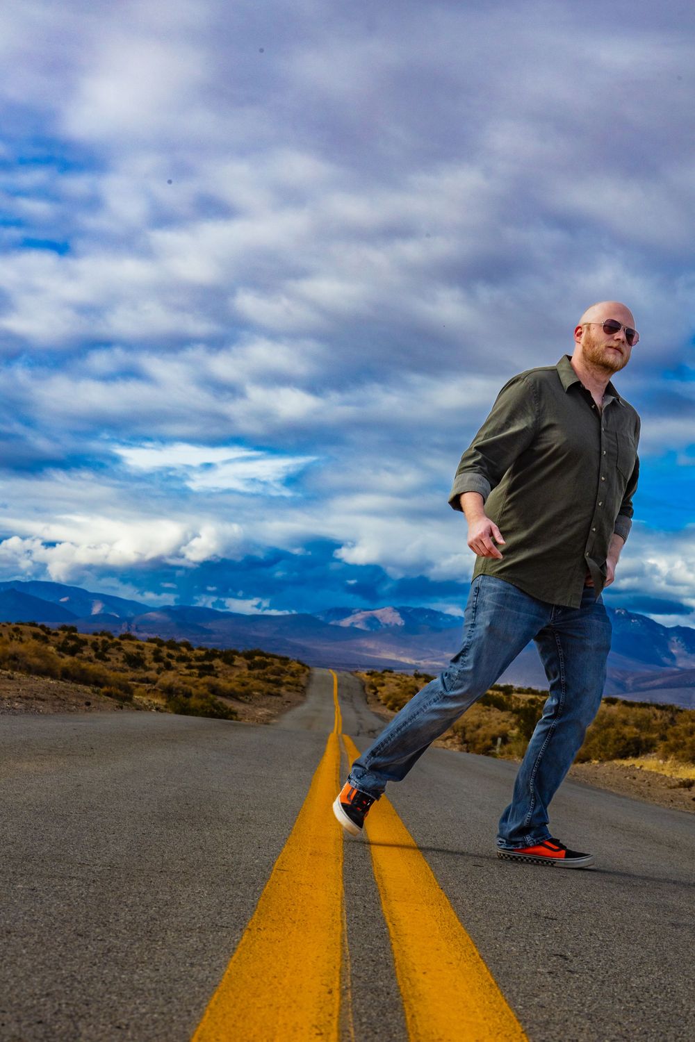 Portrait of a person in sunglasses on desert road with mountain landscape by Zeus Holbrook Wedding Photographer