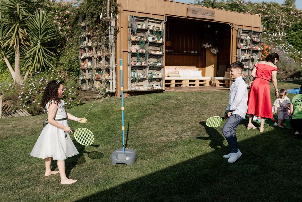 People playing outdoor lawn games with a wall of vintage crates in the background at a garden party.