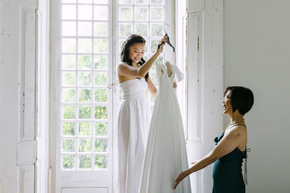 Bride smiling while holding wedding dress during preparations with family in Lisbon destination wedding