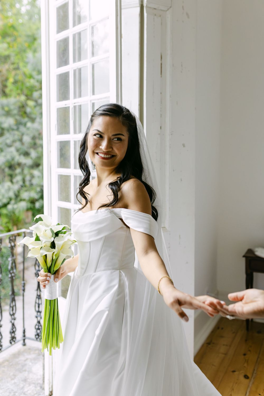 Bride holding bouquet by the window in natural light during wedding preparations in Lisbon Portugal