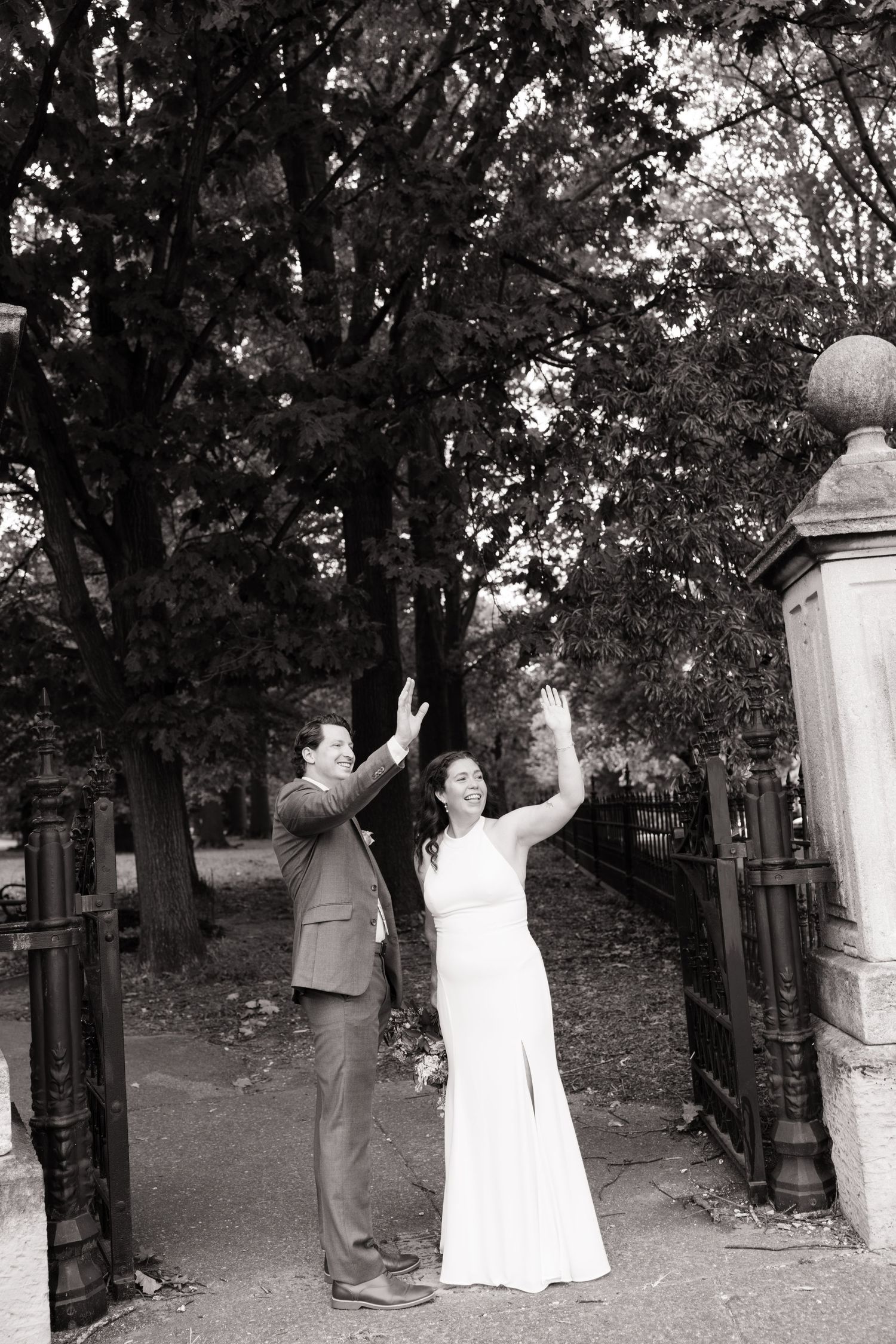 Married couple waving at passing cars at Lafayette Square in St. Louis after their wedding.